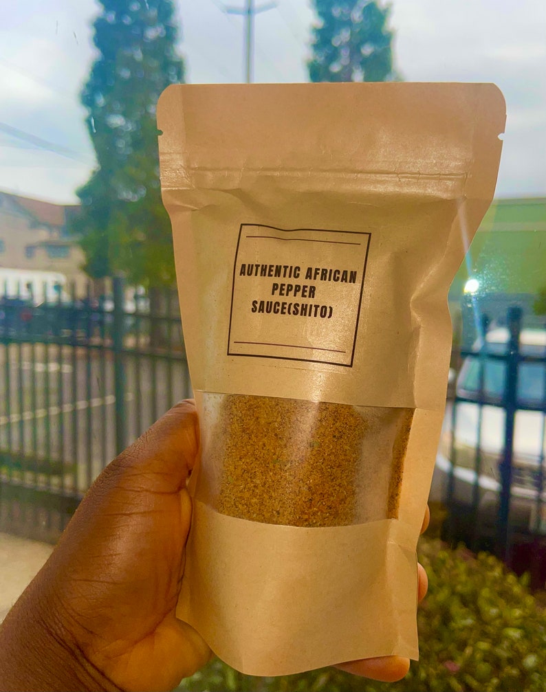 Peut inclure: Un sachet en papier brun avec une fen&ecirc;tre transparente montrant une poudre brune &agrave; l'int&eacute;rieur. Le sachet porte une &eacute;tiquette indiquant "AUTHENTIC AFRICAN PEPPER SAUCE(SHITO)"