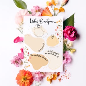 May include: A white card with the text "Liebes Brautpaar..." surrounded by colorful flowers. The card has beige shapes with fill-in-the-blank prompts like "Mein Name:" and "Liebe ist:" for a wedding guest book.