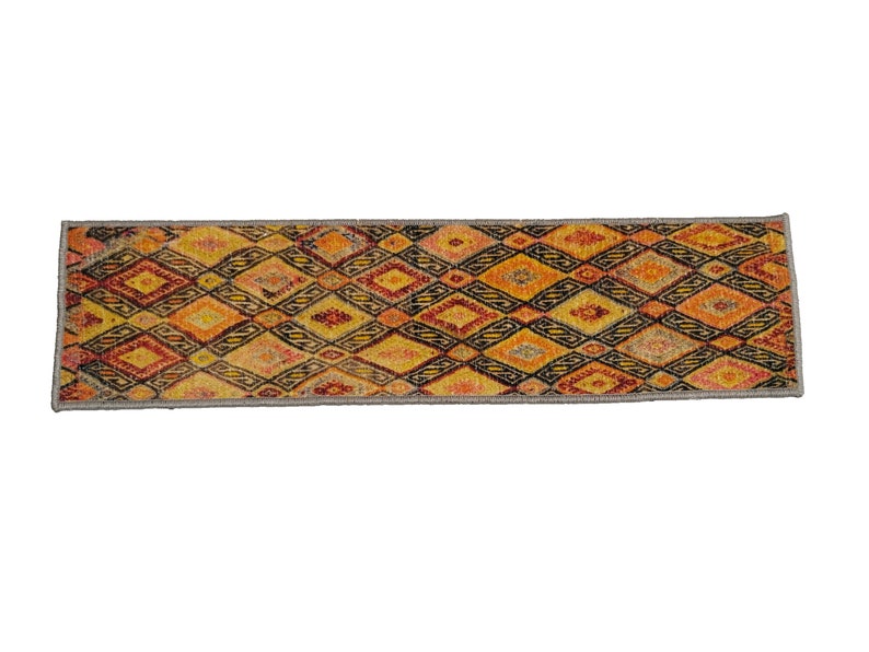 May include: A long, narrow rug with a geometric pattern in shades of orange, yellow, red, and black. The rug has a gray border.