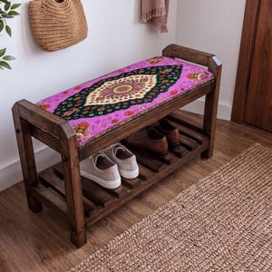 a wooden bench with a colorful, patterned seat cushion, placed in a room with a woven basket and a rug on the floor.
