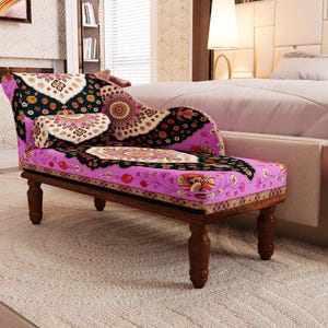 A colorful, patterned armchair with a floral design sits in a bedroom, accompanied by a white bed and a beige headboard.