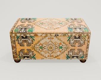 May include: A rectangular storage ottoman with a patterned fabric top and wooden legs. The fabric features a traditional Turkish kilim design in shades of beige, brown, green, and blue.