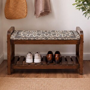 A wooden bench with a patterned seat and storage space for shoes, situated in a hallway with a woven basket and a potted plant nearby.