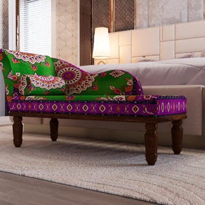 a colorful, patterned bench with a green and purple cushion, placed in a bedroom setting with a white headboard and a rug on the floor.