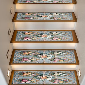 Könnte beinhalten: Stufen mit floralem Design. Die Stufen haben einen hellblauen Hintergrund mit einem sich wiederholenden Muster aus rosa, gelben und weißen Rosen, akzentuiert durch goldene Schnörkel. Die Stufen sind rechteckig und passen auf Holztreppen.