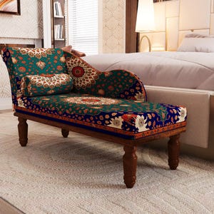 a colorful, patterned armchair with a wooden frame, placed in a bedroom setting with a bed and a bookshelf visible in the background.
