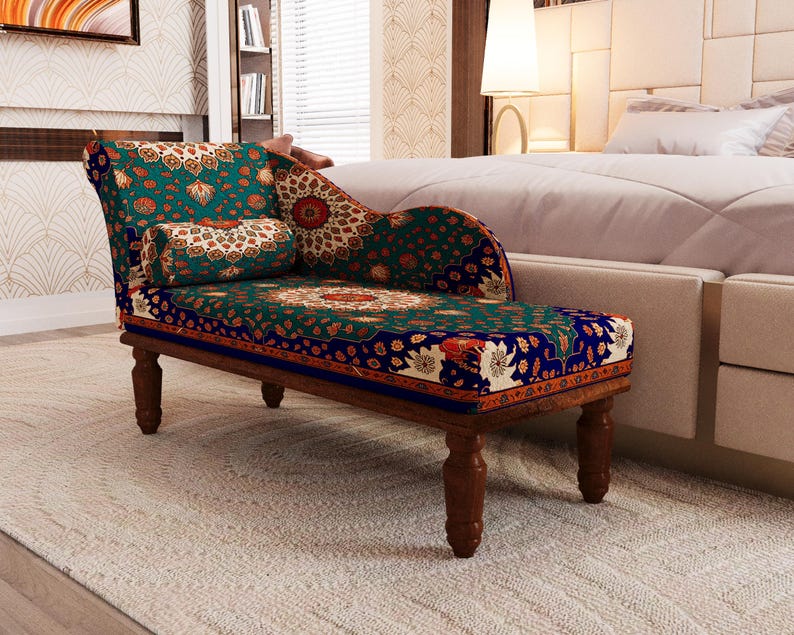 a colorful, patterned armchair with a wooden frame, placed in a bedroom setting with a bed and a bookshelf visible in the background.