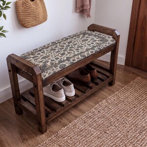 A wooden bench with a woven seat and storage space underneath, situated in a room with a woven basket and a rug on the floor.