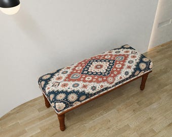 May include: A rectangular bench with a patterned cushion featuring a central medallion design in red, blue, and cream. The bench has four wooden legs and a decorative border. The overall style is reminiscent of a traditional rug.