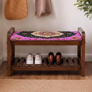 A wooden bench with a colorful patterned seat, displaying a pair of shoes on the lower shelf, and a woven basket next to it.