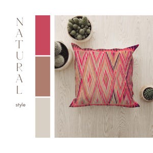 Könnte beinhalten: Dekoratives Zierkissen mit geometrischem Muster in Rosa-, Orange- und Brauntönen. Das Kissen liegt auf einer hellen Holzoberfläche, mit kleinen Topf-Kakteen in der Nähe. Die Wörter "NATURAL" und "style" sind vertikal geschrieben.