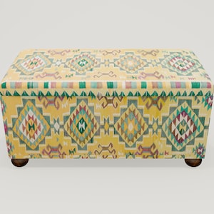 May include: A yellow storage ottoman with a colorful geometric pattern. The ottoman has wooden legs.