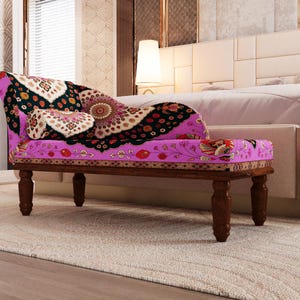 A colorful, patterned bench with a floral design sits in a bedroom with a white headboard and a beige rug.