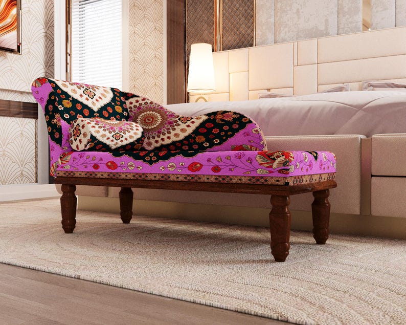 A colorful, patterned bench with a floral design sits in a bedroom with a white headboard and a beige rug.