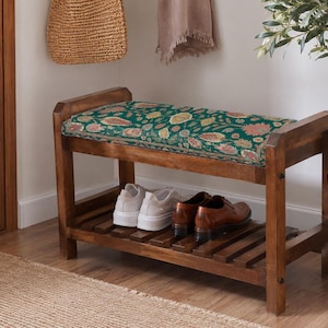 A wooden bench with a green and pink floral cushion, displaying a pair of white shoes on the lower shelf.