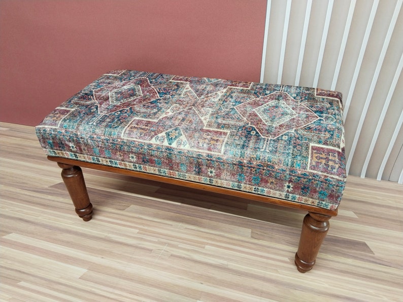 Puede incluir: Un banco de madera con un coj&iacute;n de tela estampado. El coj&iacute;n presenta un dise&ntilde;o geom&eacute;trico colorido en tonos azules, rojos y beige.