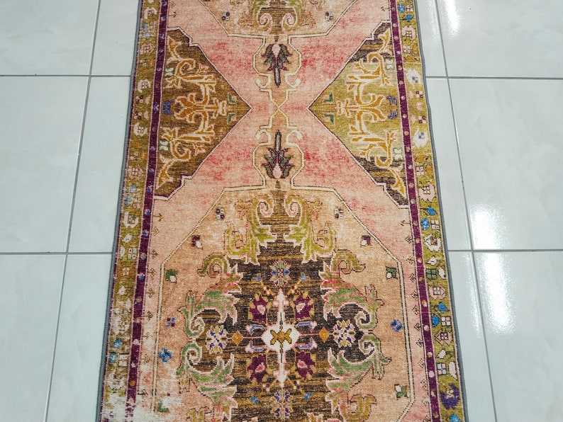 K&ouml;nnte beinhalten: Ein Vintage-Teppich in den Farben Rosa, Beige, Gr&uuml;n und Braun. Der Teppich hat ein traditionelles persisches Design mit komplizierten Blumenmustern.