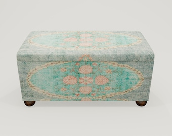 May include: A teal and cream patterned storage ottoman with wooden legs. The ottoman has a floral design with pink accents.