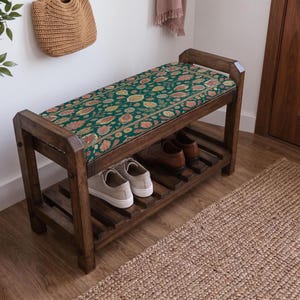 a wooden bench with a colorful floral patterned cushion, placed in a hallway with a woven basket and a rug on the floor.