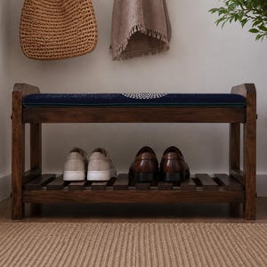 A wooden bench with a blue cushion, displaying a pair of shoes on the lower shelf, and a woven basket on the right side.