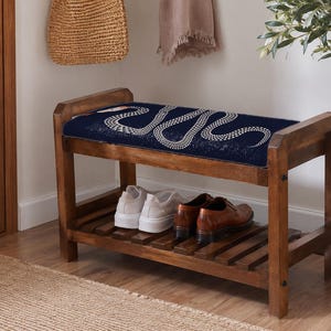 A wooden bench with a blue cushion and a pair of brown shoes placed on it, situated in a hallway with a woven basket and a potted plant nearby.