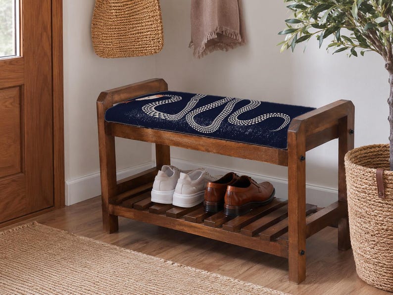 A wooden bench with a blue cushion and a pair of brown shoes placed on it, situated in a hallway with a woven basket and a potted plant nearby.