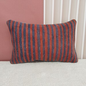 Puede incluir: Una almohada de rayas con rayas rojas y azules. La almohada está hecha de una tela suave y tejida.
