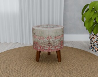 May include: A round, floral patterned ottoman with four wooden legs. The ottoman is sitting on a beige rug.