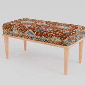 Puede incluir: Un banco de madera con un cojín estampado en marrón y azul. El banco tiene un diseño sencillo con cuatro patas.