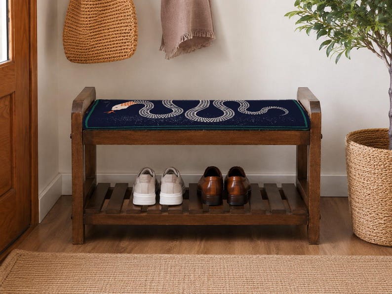 A wooden bench with a blue and white snake design on the seat, displaying a pair of shoes on the lower shelf.
