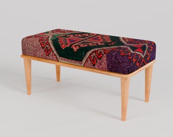 May include: A wooden bench with a colourful patterned cushion. The cushion has a geometric design in shades of red, green, purple, and black.
