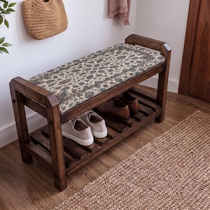 A wooden bench with a woven seat and storage space underneath, situated in a room with a woven basket and a rug on the floor.
