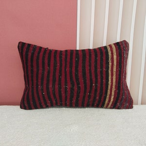 May include: A red, black, and gold striped throw pillow with a woven texture.