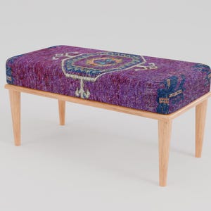 Puede incluir: Un banco de madera con un cojín estampado en morado y azul. El cojín tiene un diseño geométrico con un octógono central.