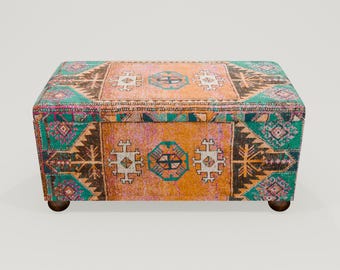 May include: A colorful storage ottoman with a traditional Turkish rug pattern. The ottoman has a rectangular shape and wooden legs.