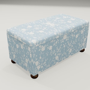 May include: A light blue storage ottoman with a floral pattern and wooden legs.