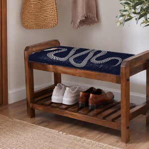 A wooden bench with a blue cushion and a pair of brown shoes placed on it, situated in a hallway with a woven basket and a potted plant nearby.