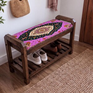 a wooden bench with a colorful, patterned seat cushion, placed in a room with a woven basket and a rug on the floor.