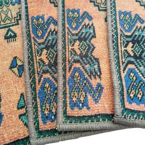 Puede incluir: Primer plano de un conjunto de cuatro alfombras tejidas de colores con patrones geom&eacute;tricos en tonos azules, verdes y naranjas. Las alfombras tienen un borde con flecos y est&aacute;n hechas de un material suave y texturizado.