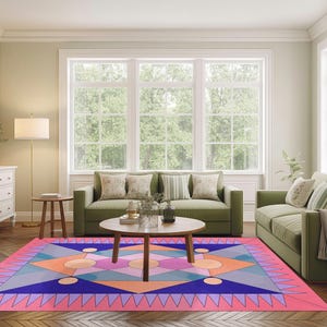 Peut inclure: Un tapis de sol géométrique coloré avec une bordure rose, présentant des triangles, des losanges et des cercles dans des tons de bleu, orange et violet. Le tapis est dans un salon avec des canapés verts et une table basse en bois.