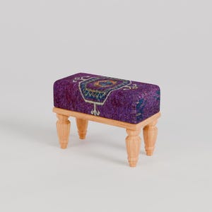 May include: A small purple and blue patterned ottoman with wooden legs.