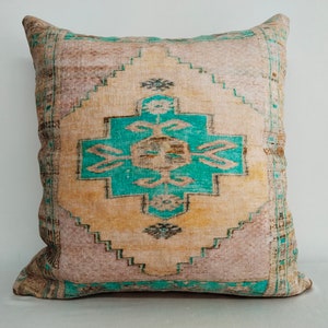 May include: A decorative pillow with a turquoise and beige patterned design. The pillow is made from a soft, woven fabric and has a square shape.