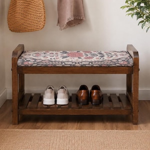 A wooden bench with a floral patterned seat and storage space underneath, placed in a hallway with a woven basket and a potted plant nearby.