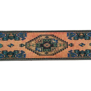 Puede incluir: Una alfombra larga y estrecha con un dise&ntilde;o turco tradicional. La alfombra tiene un fondo melocot&oacute;n con un patr&oacute;n central en forma de diamante en tonos de azul, verde y negro. El patr&oacute;n de diamante est&aacute; rodeado de formas geom&eacute;tricas m&aacute;s peque&ntilde;as en los mismos colores. La alfombra tiene un borde gris oscuro.
