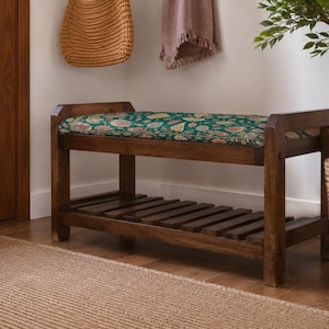 a wooden bench with a colorful floral patterned cushion, placed on a wooden floor next to a woven basket and a potted plant.