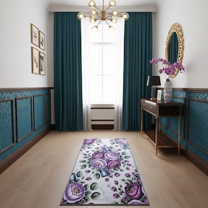 May include: A hallway with teal walls, dark wood trim, and a floral rug. The rug features large purple flowers on a white background. A gold mirror and chandelier add elegance to the space.