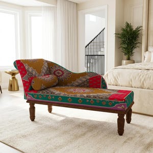May include: A chaise longue featuring a vibrant, multi-coloured fabric with intricate mandala-inspired patterns in shades of mustard yellow, deep red, and teal green. The piece includes a matching cylindrical bolster pillow and dark wooden legs.