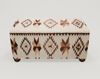 May include: A white storage bench with a brown and beige geometric pattern. The bench has a rectangular shape and wooden legs.