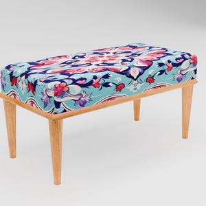 May include: A wooden bench with a blue and pink floral patterned cushion. The bench has four legs and a rectangular shape.