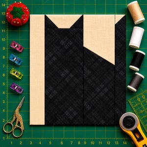 May include: A square quilt block featuring a stylised black cat silhouette made of fabric with a subtle plaid pattern against a solid beige background. The block is surrounded by sewing notions including a red pincushion, colourful clips, gold stork scissors, four spools of thread, and a rotary cutter on a green cutting mat.